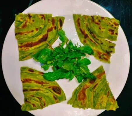 Green dosa served with chutney and fresh herbs